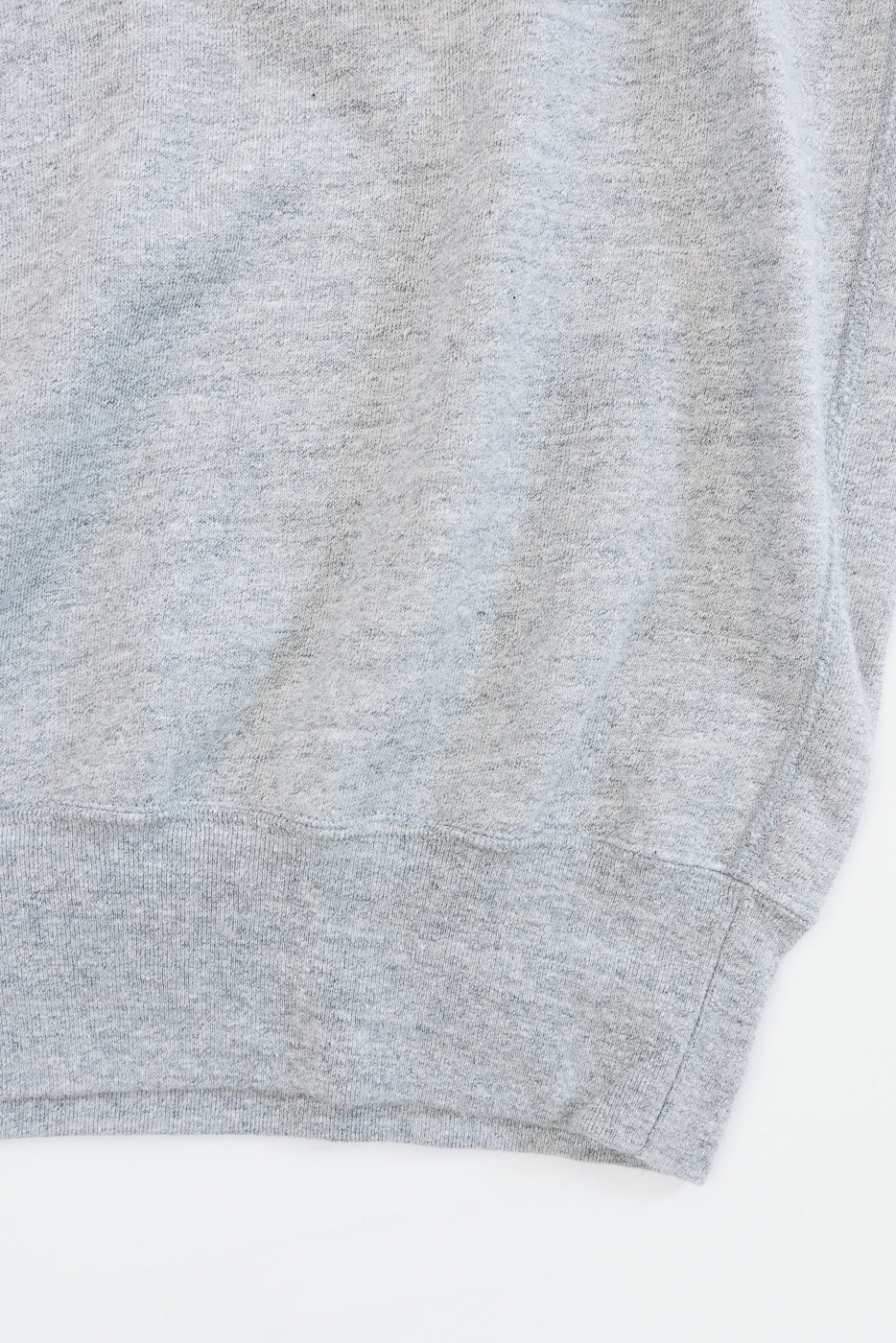 Close-up of heather gray sweatshirt hem, showing ribbed knit texture and clean stitching detail