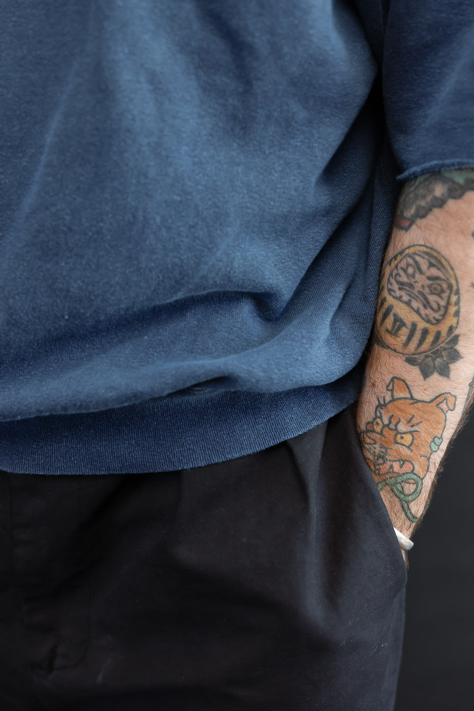 Close-up of male model's side, showcasing navy tee's ribbed hem and sleeve texture, athletic build