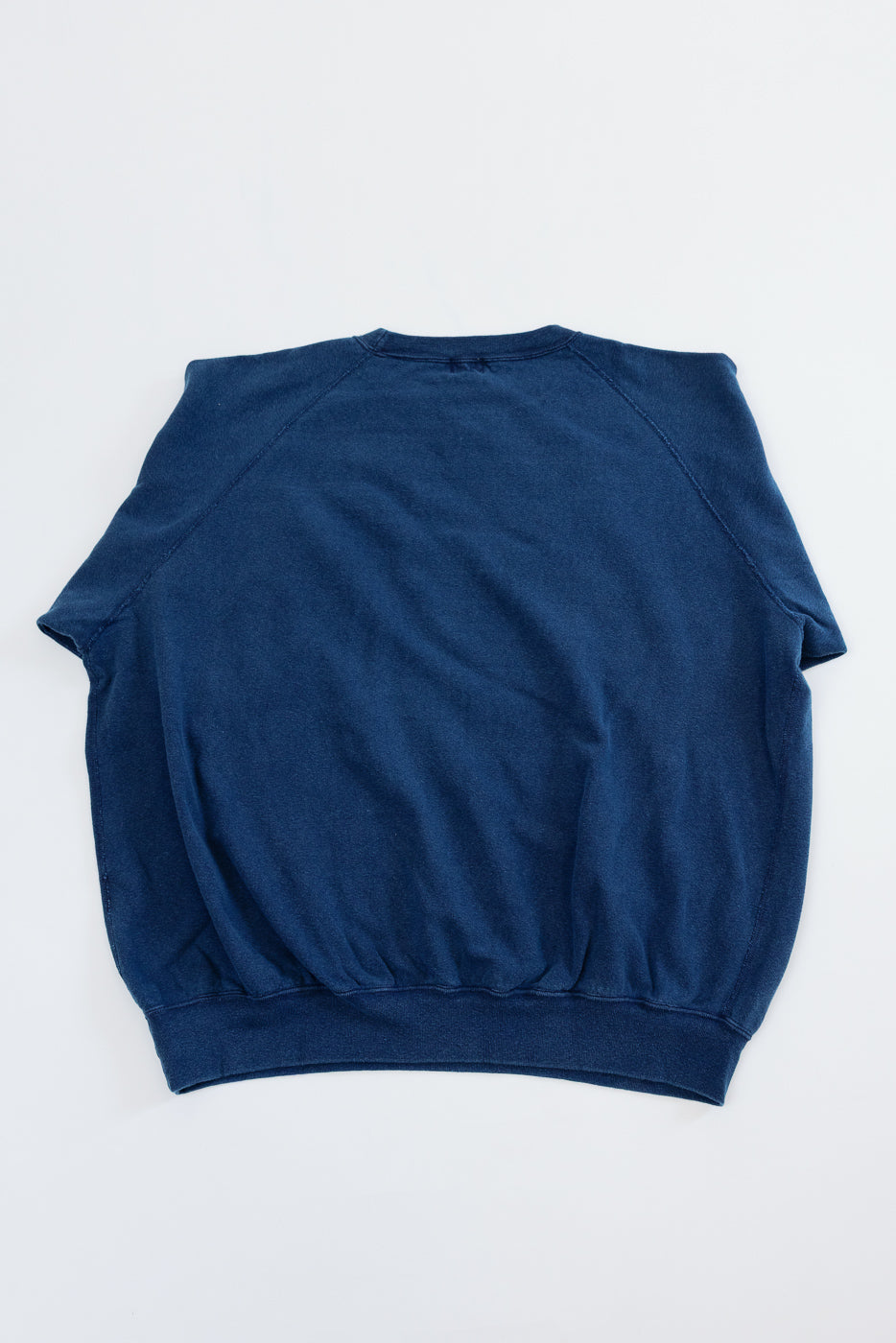 Back view flat lay of navy blue raglan sleeve crewneck sweatshirt with ribbed hem
