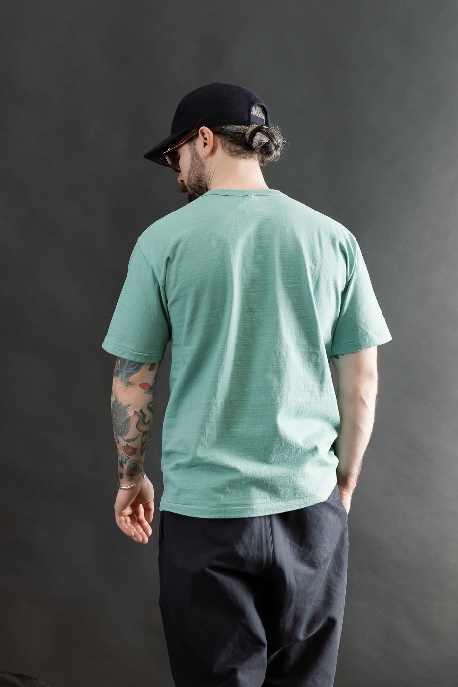 Male model 5'9, 165lbs, athletic build wearing Dubble Works emerald tee, back view, full body