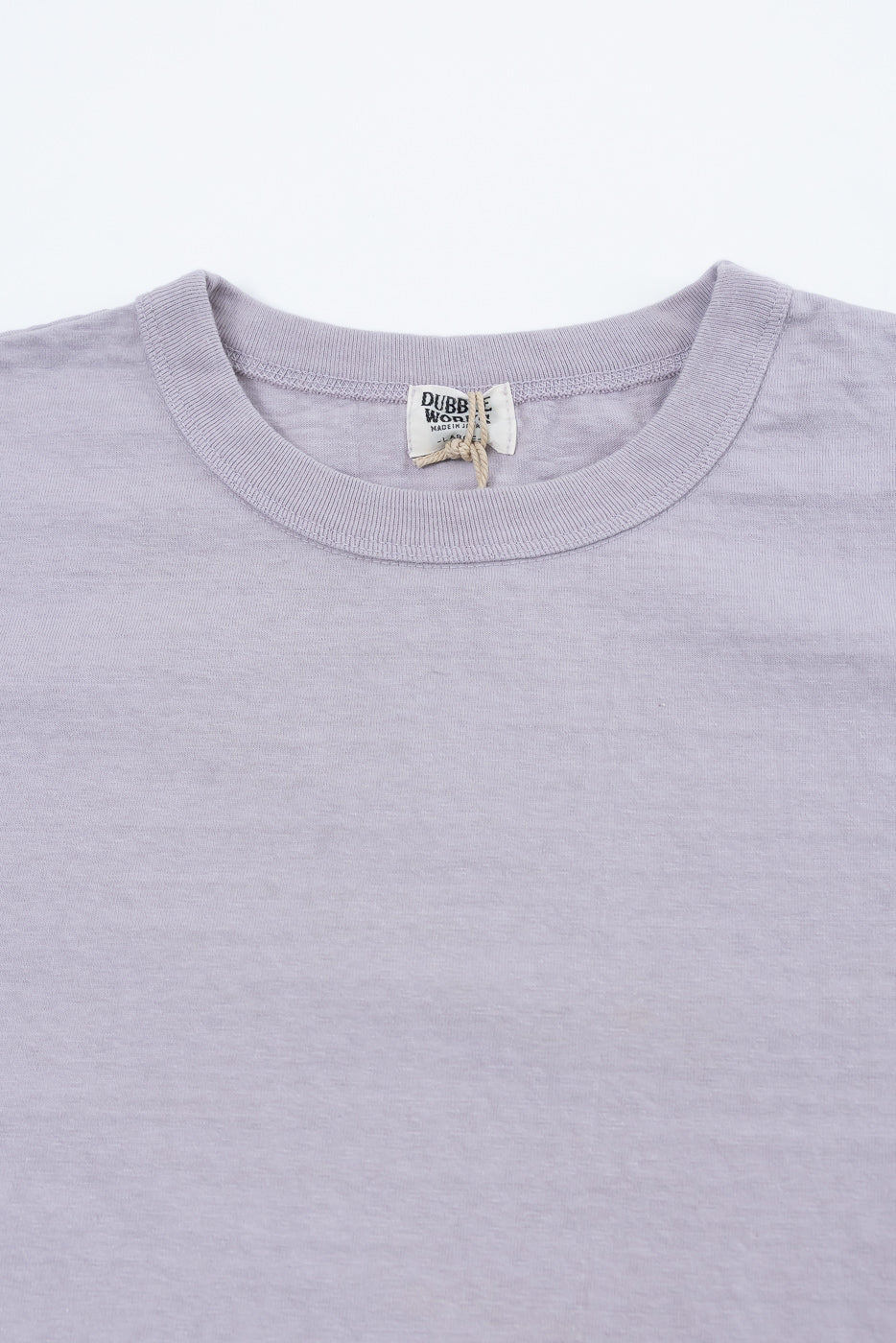 Close-up of Dubble Works lavender cotton tee front, showing crew neck, collar, and tag detail