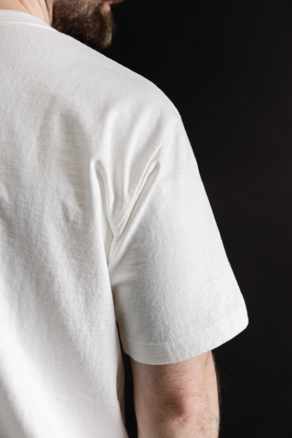 Close-up of male model's back and sleeve in off-white midweight cotton tee, athletic build