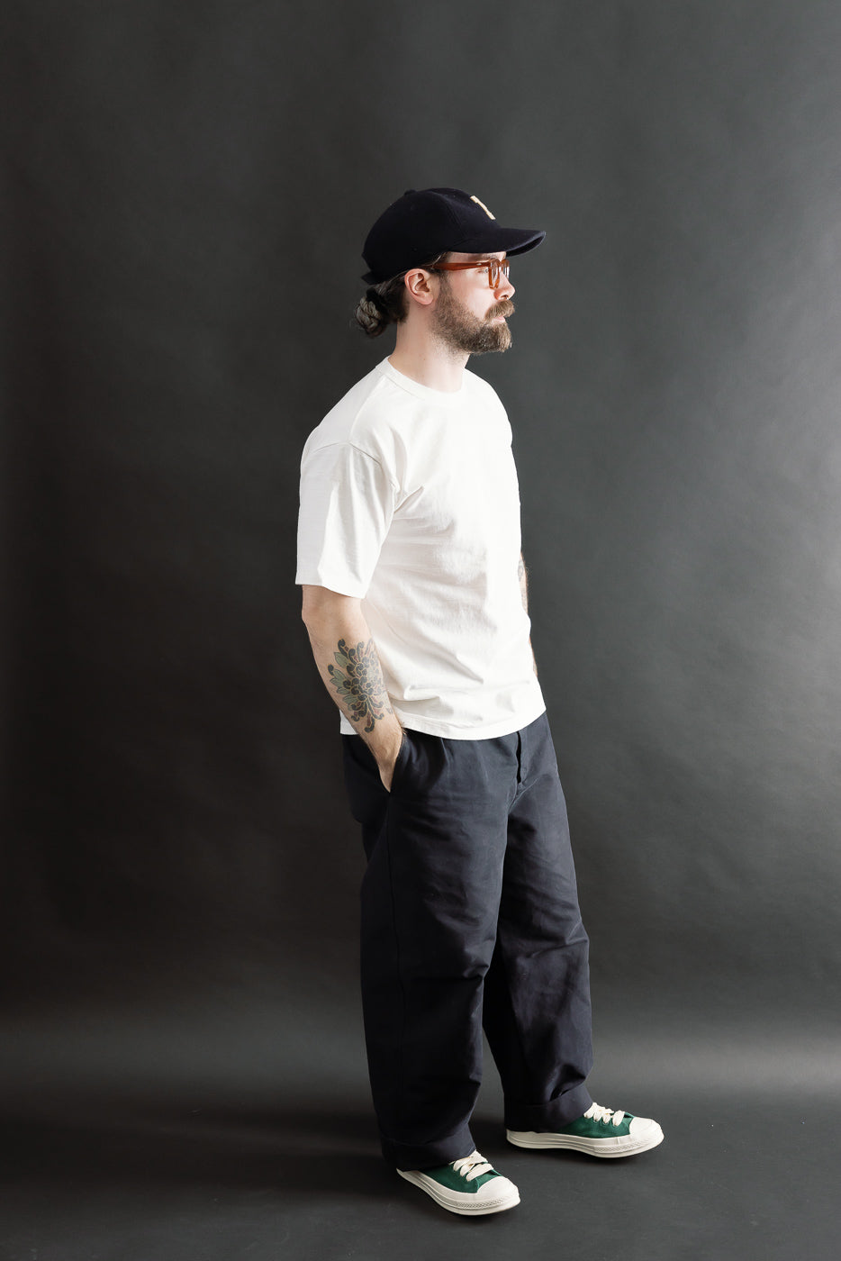 Male model 5'9 165lbs athletic build wearing off-white Dubble Works cotton tee side full body view, casual contemporary apparel at Dant