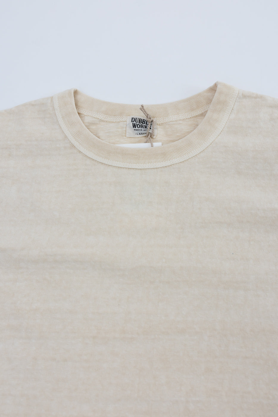 Close-up of Dubble Works Fallen Cotton Midweight Tee front, cream color, crew neck, visible neck tag, fabric texture detail at Dant