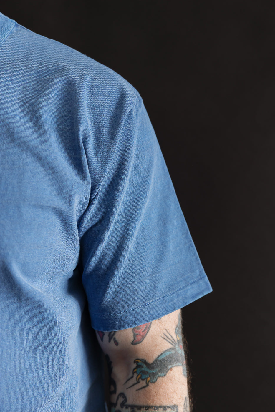 Close-up of men's light indigo short sleeve tee, left sleeve and shoulder detail on athletic 5'9