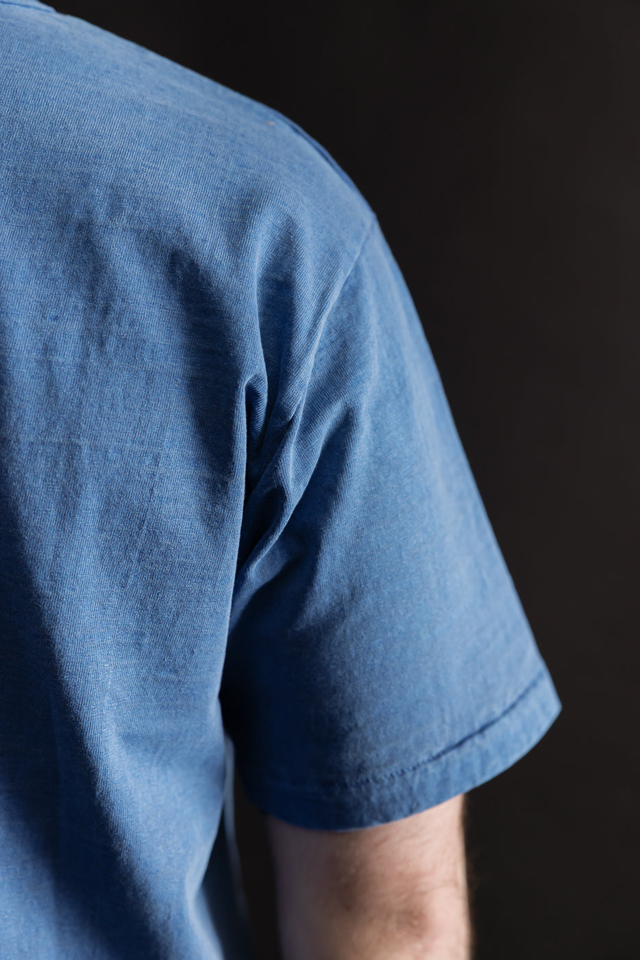 Close-up of men's Dubble Works light indigo tee sleeve and shoulder, right side view