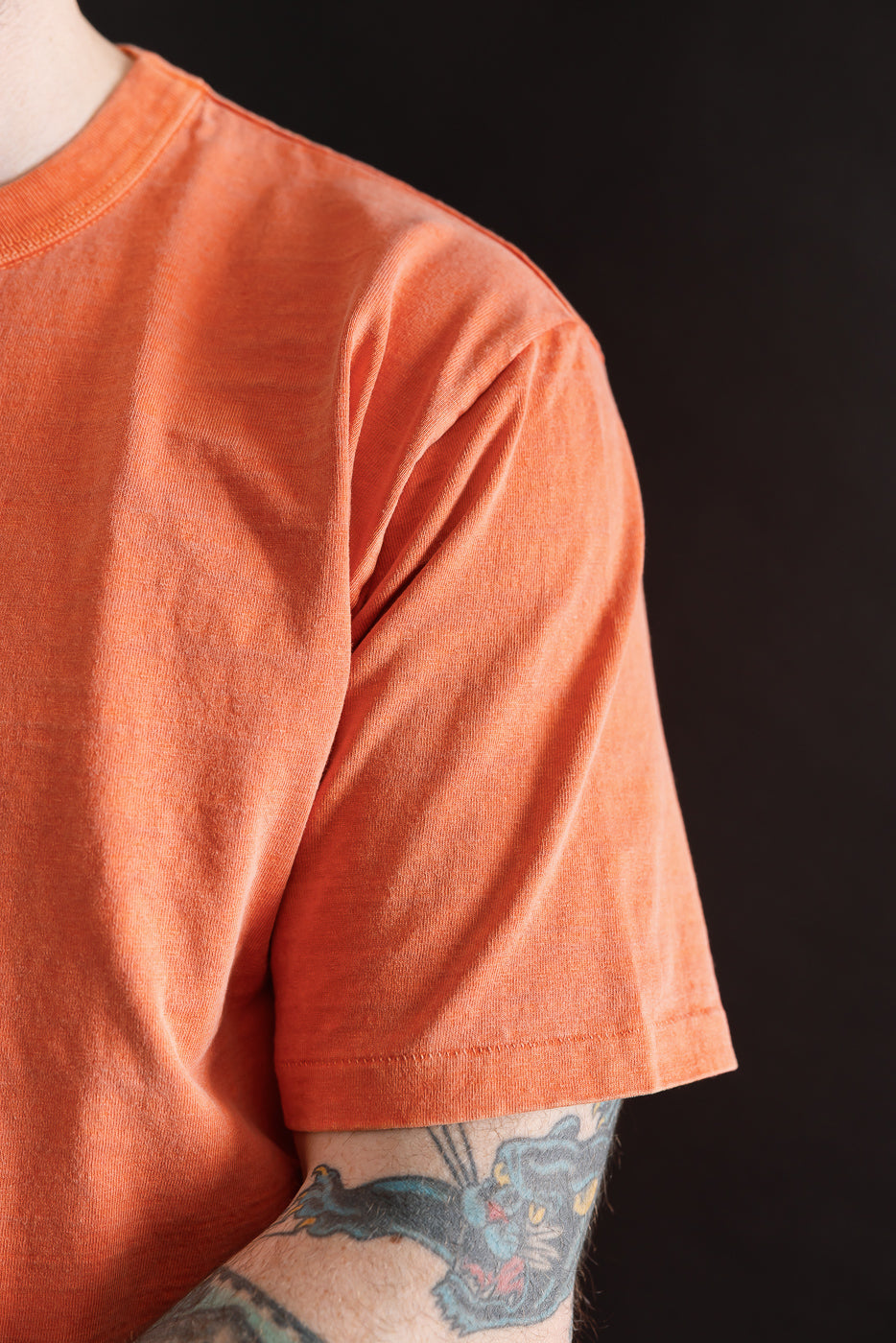 Close-up of Dubble Works Fallen Cotton Midweight orange tee, front left chest, on 5'9