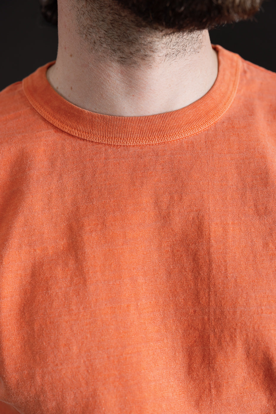 Close-up front of Dant orange midweight cotton tee, male model, showing collar and fabric texture
