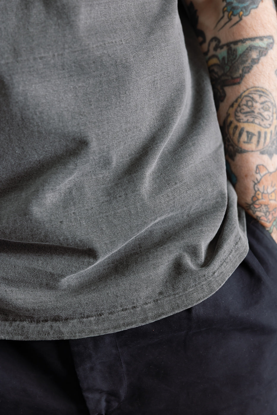 Close-up of Dubble Works Fallen Cotton Midweight Tee front hem, sumikuro color, on male model 5'9