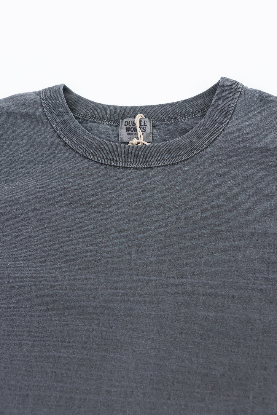 Close-up of Dubble Works Fallen Cotton Midweight Tee front, showing crewneck collar and tag detail, dark sumikuro color, fabric texture visible.