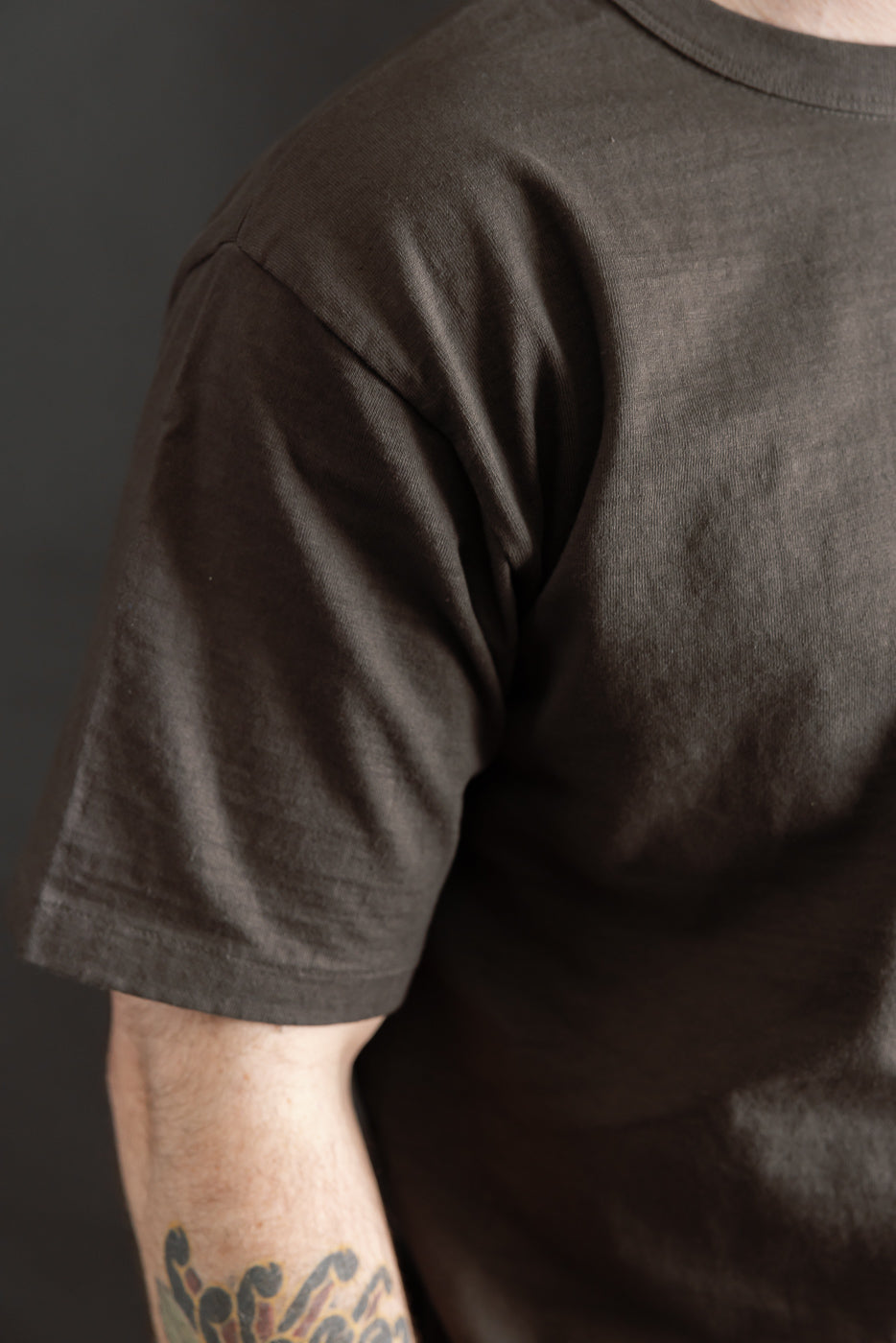 Close-up of male model’s right side in DUBBLE WORKS Sumikuro cotton tee, showing sleeve and fabric texture.