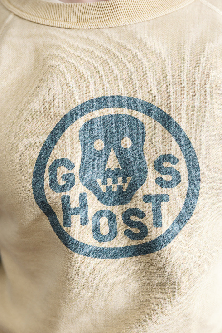 Close-up of front chest on beige sweatshirt, showing blue 