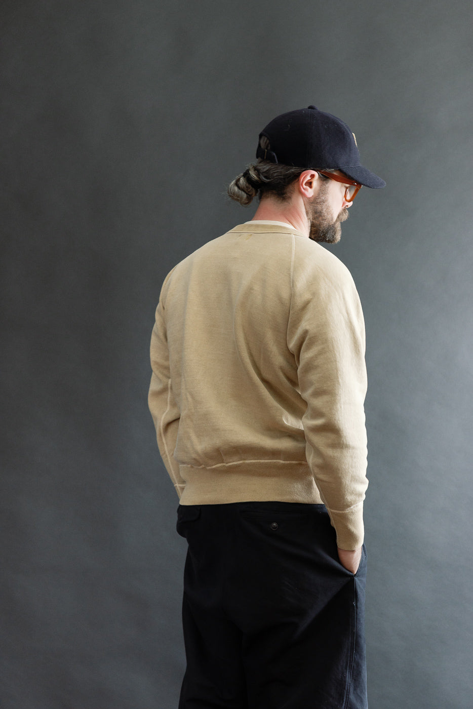 Male model, 5'9” athletic build, wearing a beige sweatshirt, back view full body