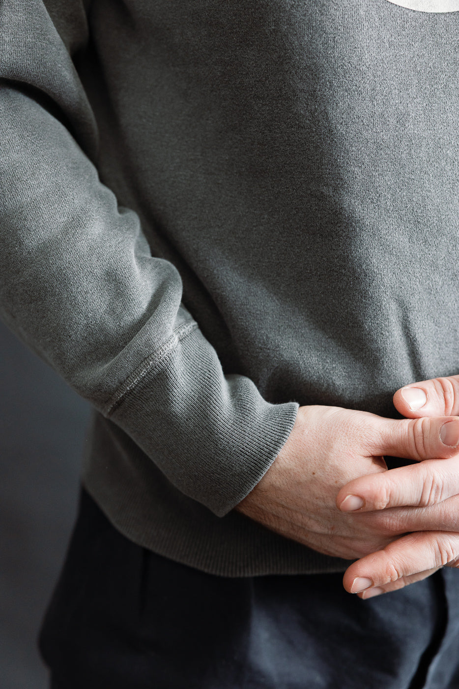 Close-up of male model's right side, showing sweatshirt sleeve cuff and hem details, athletic build, 5'9