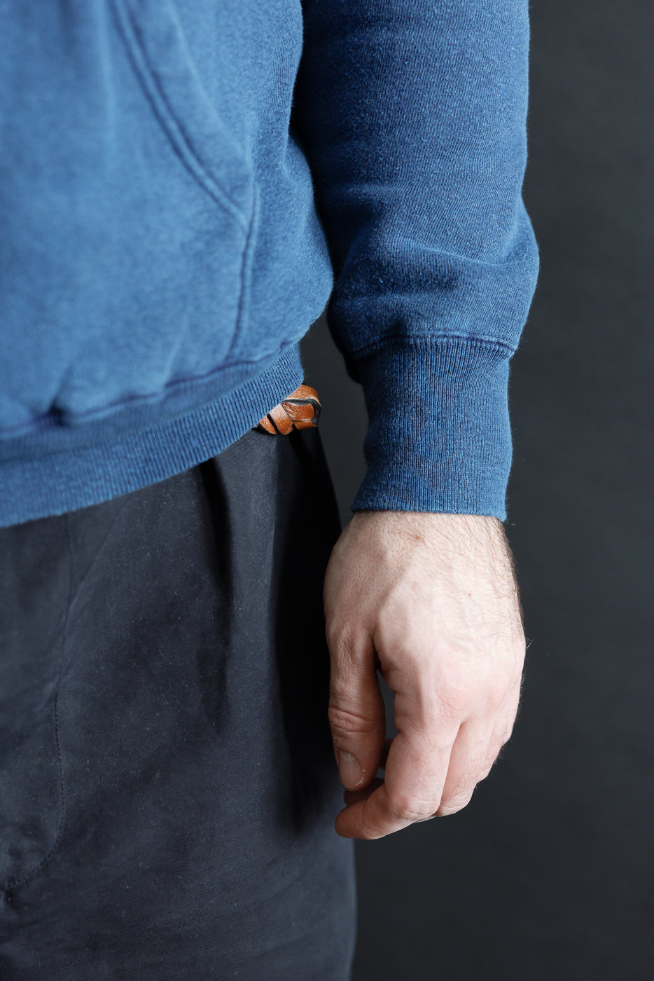 Close-up of male model’s right side waist and sleeve, indigo loopwheel hoodie, knit cuff detail, 5'9