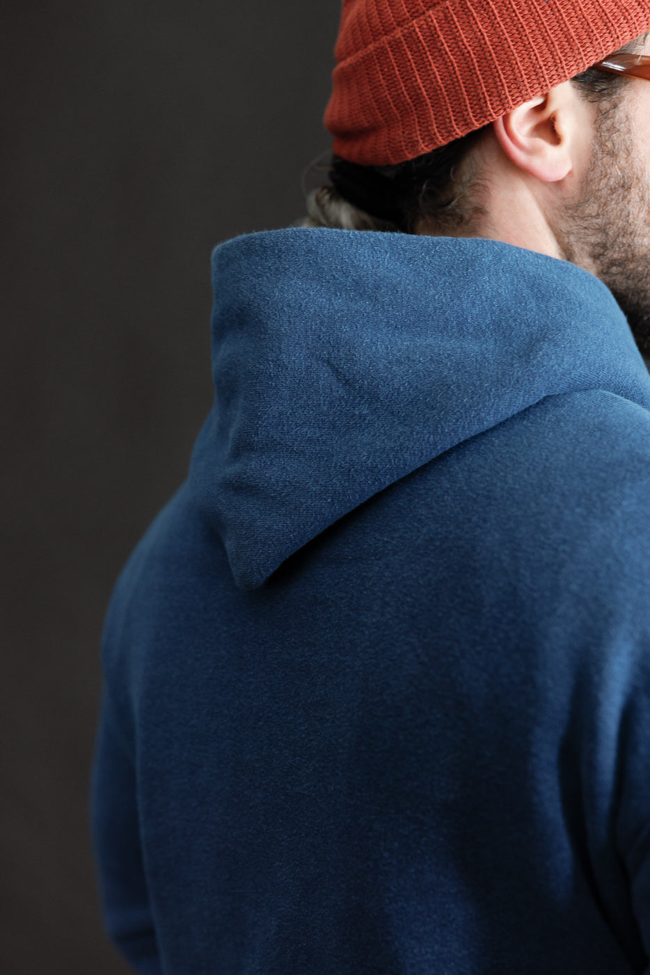 Close-up of back of indigo-dyed loopwheel hoodie hood, on male model 5'9