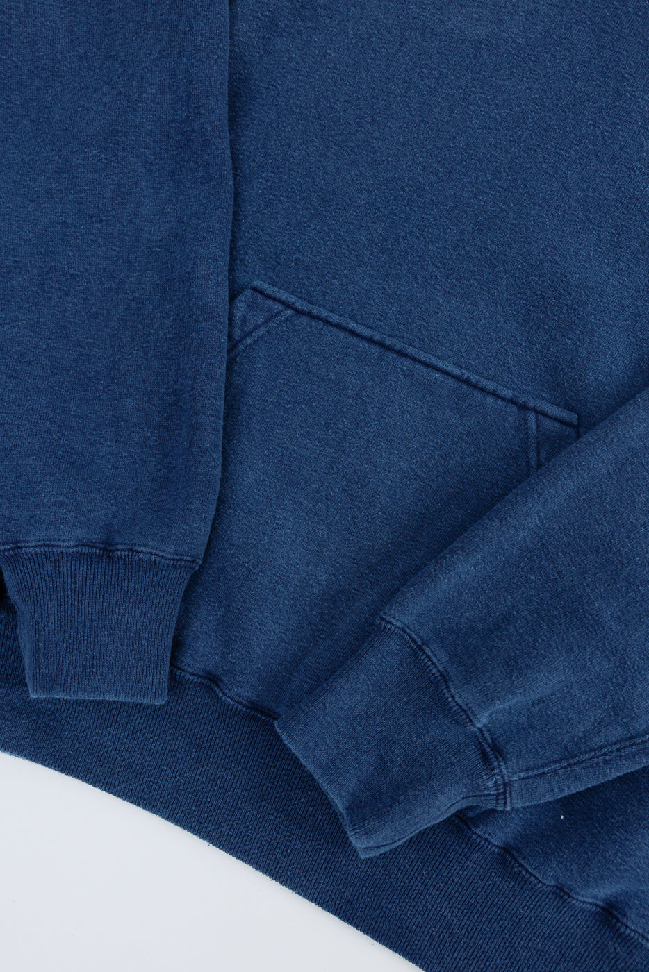 Close-up of indigo dyed loopwheel hoodie front pocket, cuffs, and fabric texture