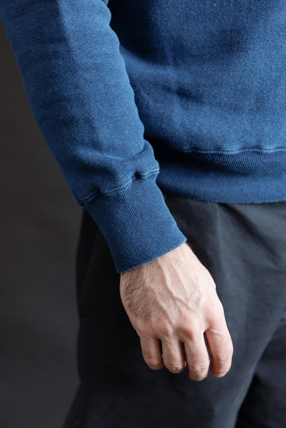 Close-up of male model’s left sleeve cuff and hem on indigo loopwheel sweatshirt, side view, 5'9