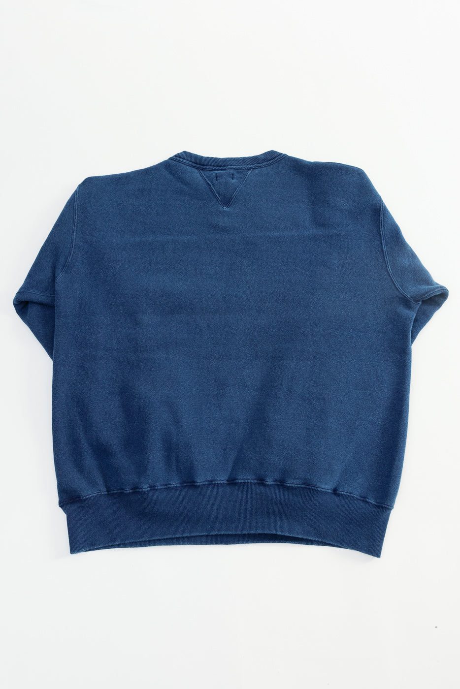 Flat lay of indigo-dyed loopwheel sweatshirt showing the back, ribbed hem and collar detail.