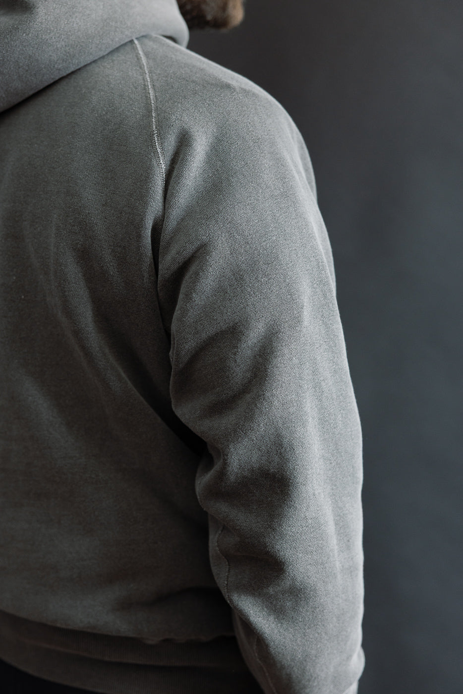 Close-up of right side and sleeve detail on male model wearing dark faded print hoodie, 5'9