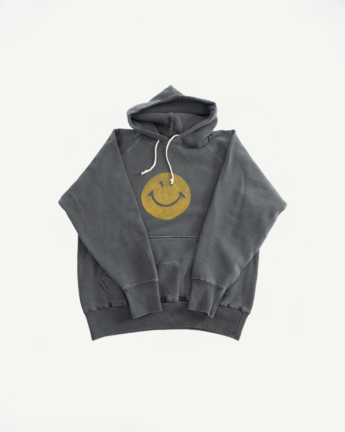 Flat lay front view of faded black smiley print pullover hoodie, showing chest graphic and kangaroo pocket.