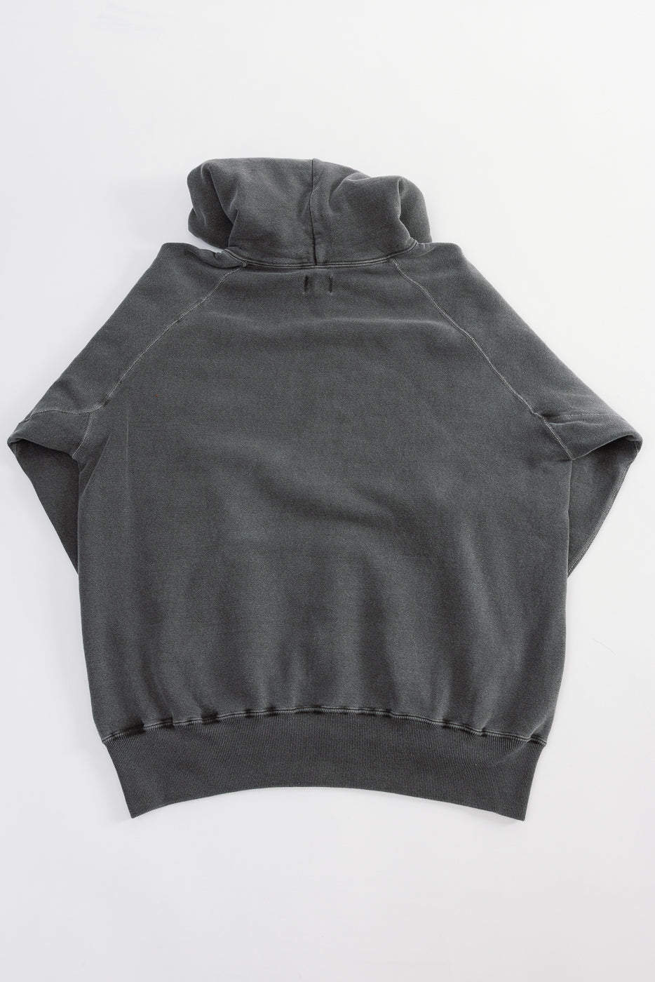 Flat lay of hoodie, back view, showing faded black fabric and ribbed hem details.