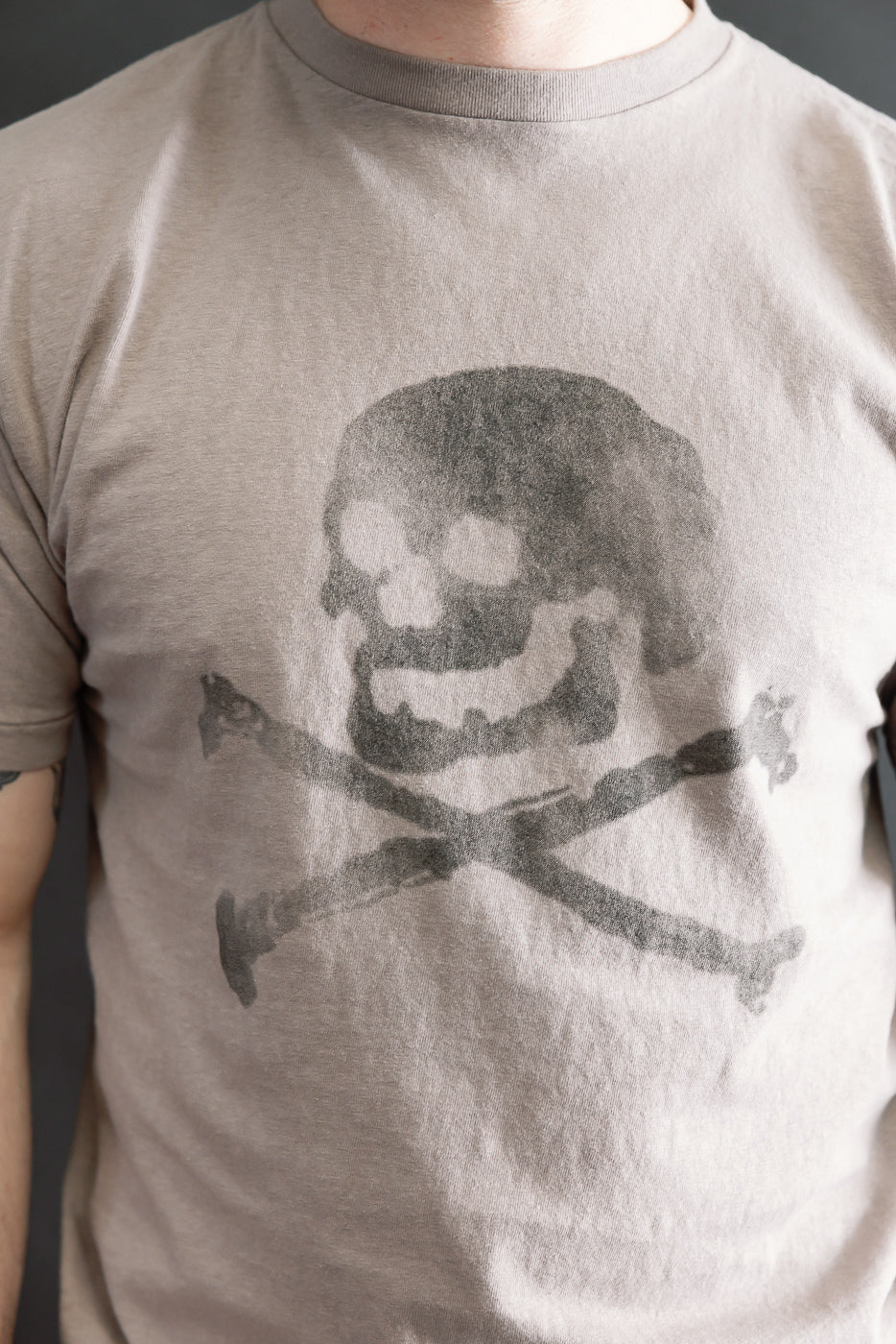 5.4oz Raffy Tenjiku Printed T-Shirt Skull & Crossbone features a large, weathered skull-and-crossbones graphic on a light-tan T-shirt, highlighting its vintage-inspired design and unique slub jersey texture.