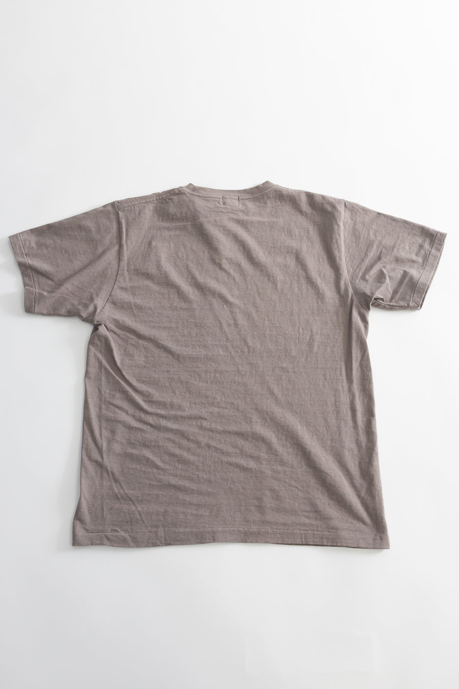 Back view of the 5.4oz Raffy Tenjiku Printed T-Shirt Skull & Crossbone - Grey, showcasing its muted taupe color, crew neck, and softly textured fabric with a tubular construction and pull-over stitch hem.