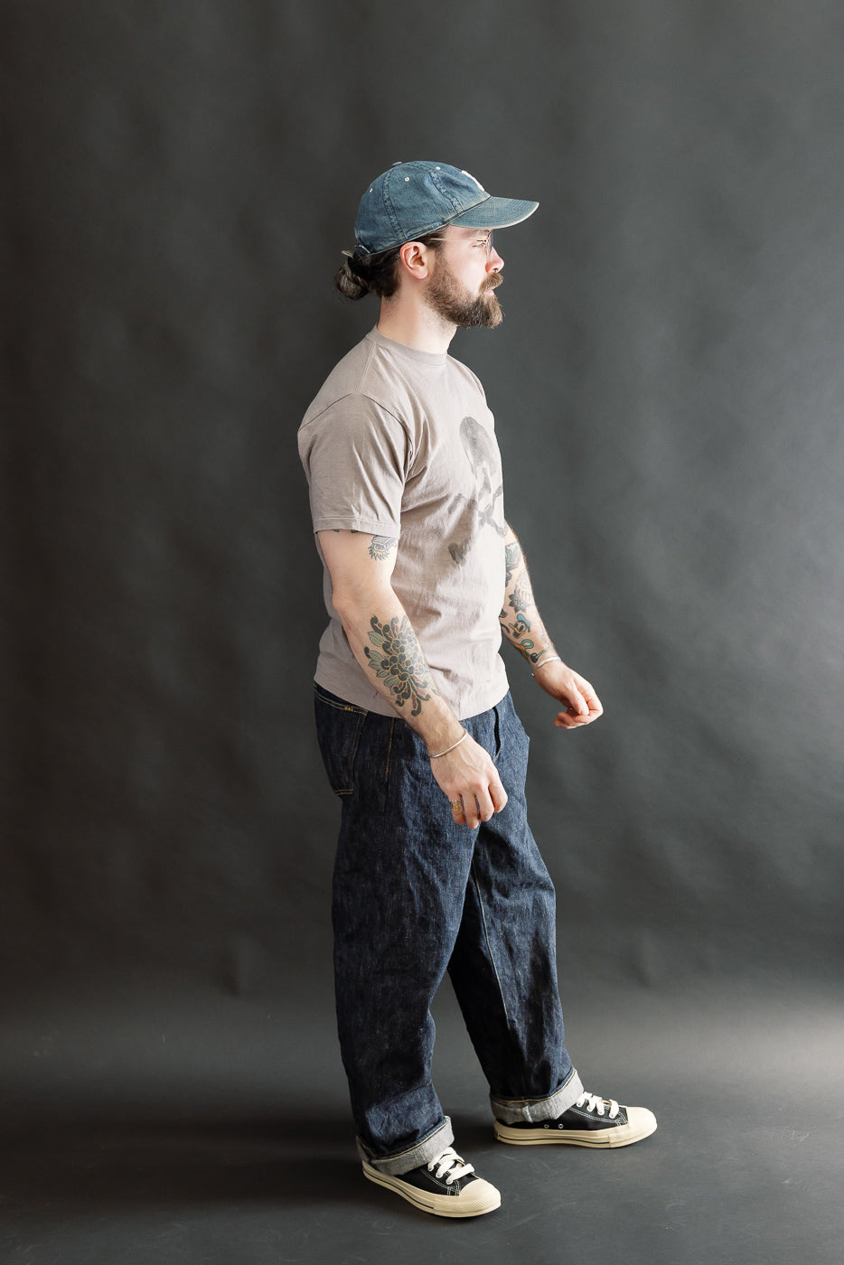 Bearded man in profile wearing the 5.4oz Raffy Tenjiku Printed T-Shirt Skull & Crossbone - Grey, highlighting its vintage-inspired American design and unique nep-like texture from Japanese organic cotton.