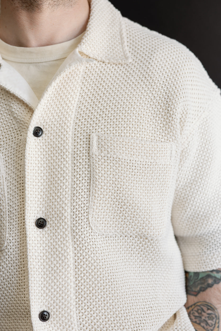 Close-up of front chest and collar of ecru cotton textured shirt on male model, 5'9