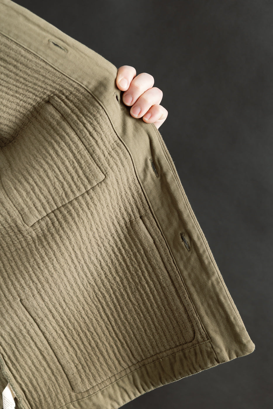 Close-up of inside front panel of fossil green jacquard shirt, highlighting pocket and stitching texture.