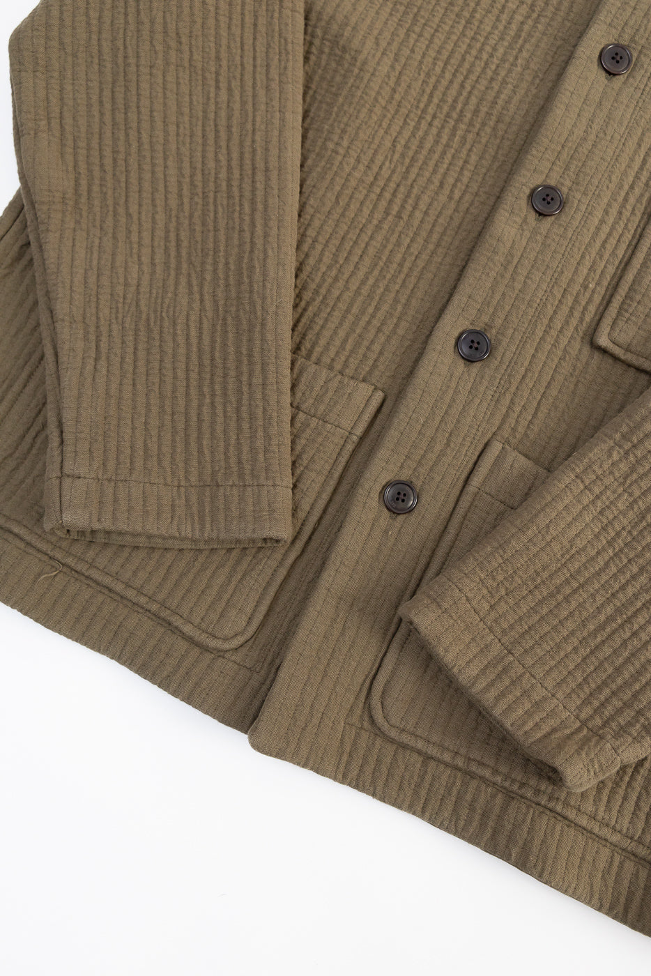 Close-up of front left side of men's fossil green jacquard shirt showing textured fabric, black buttons, and large front pockets