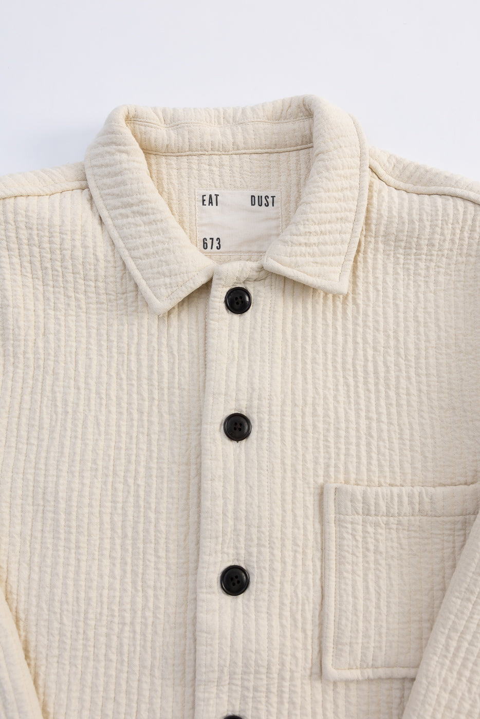 Close-up front of Eat Dust Cana Shirt in wheat jacquard, textured fabric, black buttons, patch pocket.