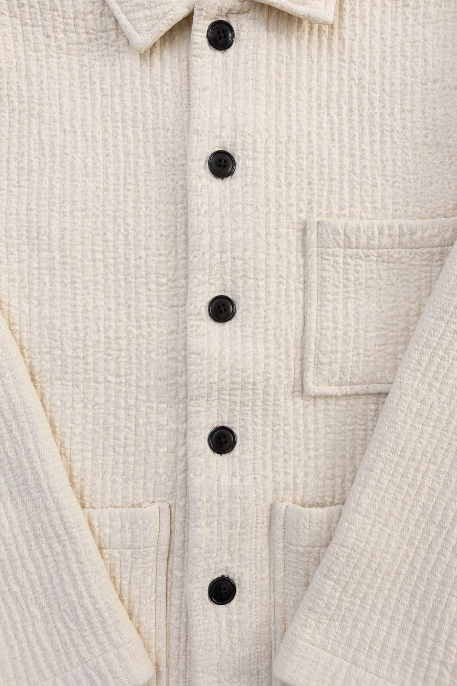 Close-up front of Cana Shirt in wheat fjord jacquard, shows textured fabric, black buttons, patch pockets, and spread collar.