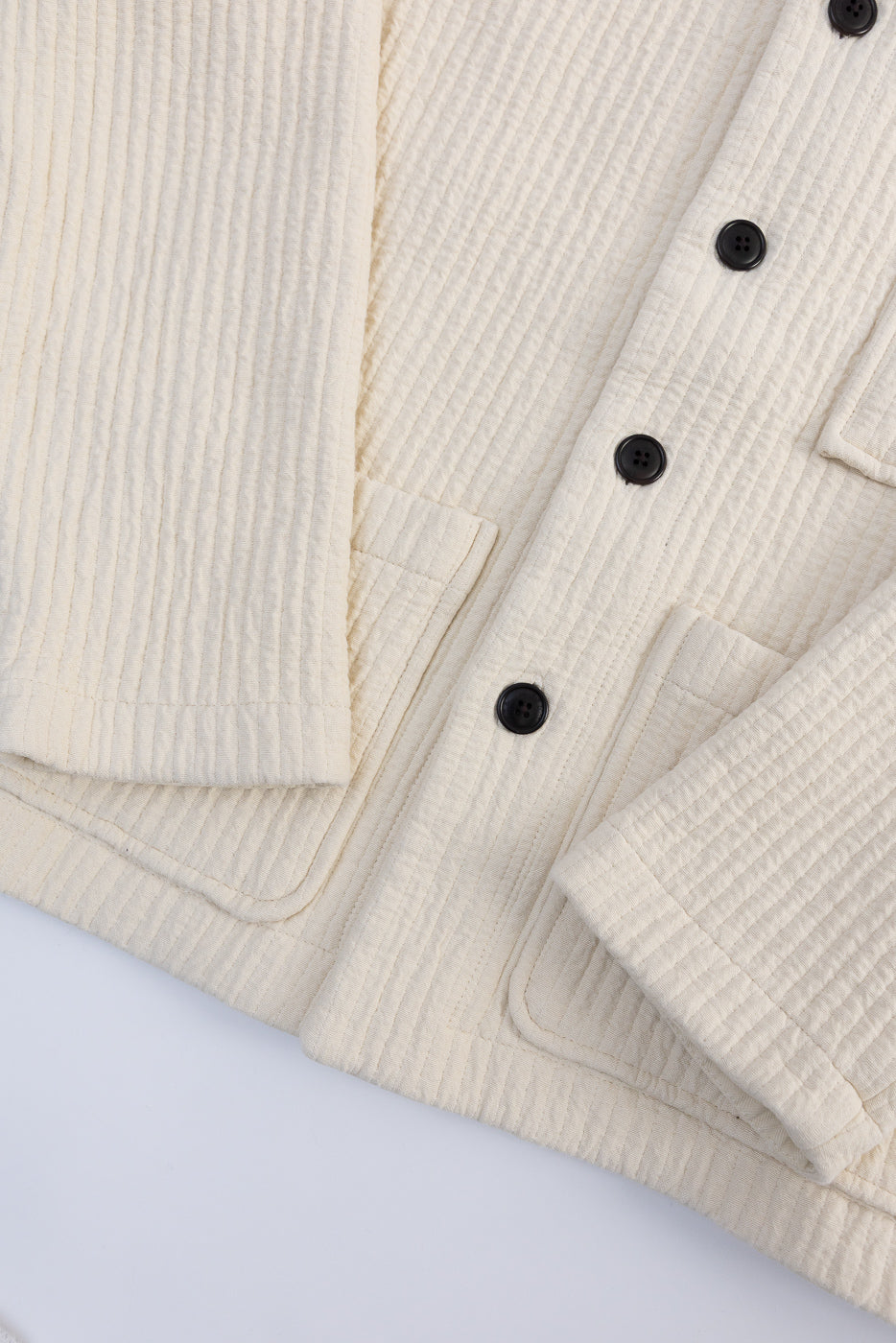 Close-up of front of Cana Shirt in wheat fjord jacquard, showing textured fabric, buttons, and pockets.