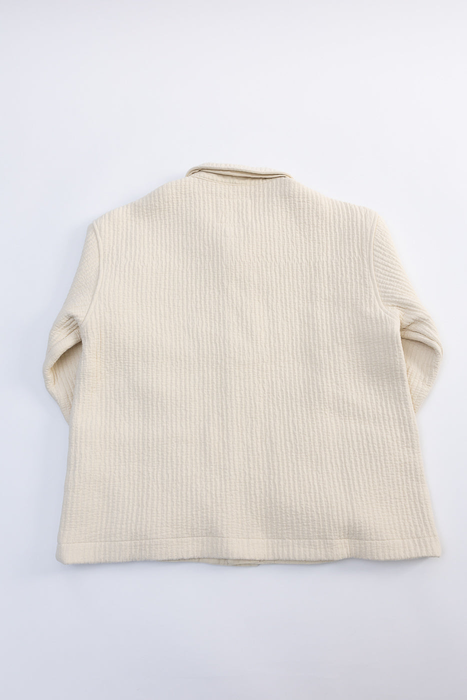 Flat lay of Eat Dust Cana Shirt in wheat Fjord jacquard, back view, textured cream fabric.