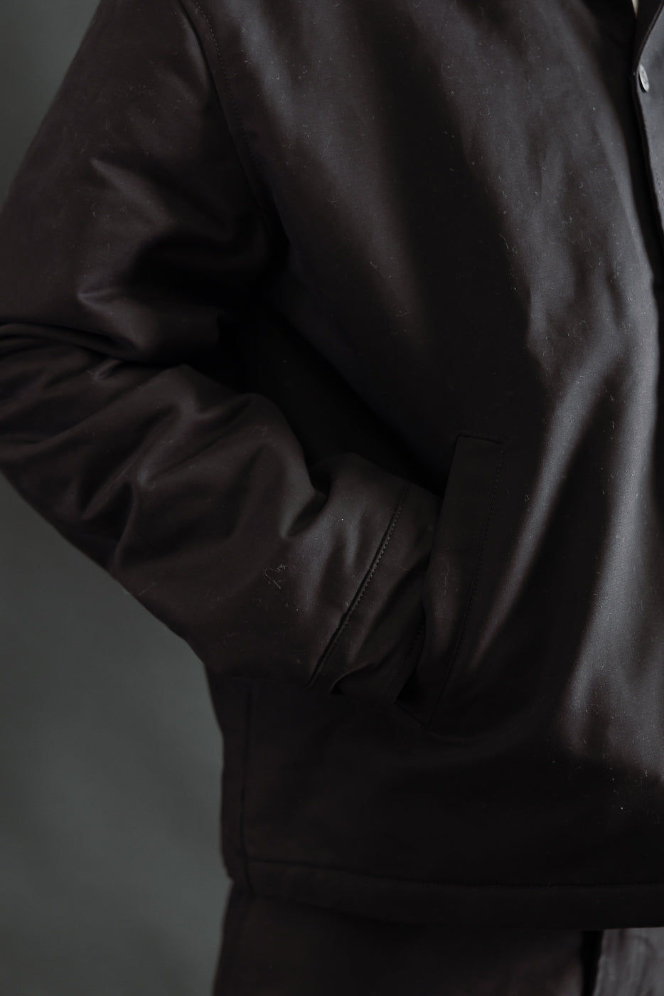 Close-up of Eat Dust Dago Jacket front left side, black cotton, male model with hand in pocket
