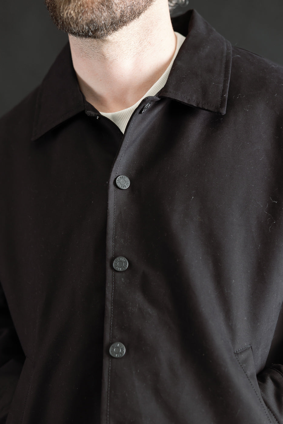 Close-up front of black Nebraska cotton jacket, classic collar, snap buttons, male model 5'9