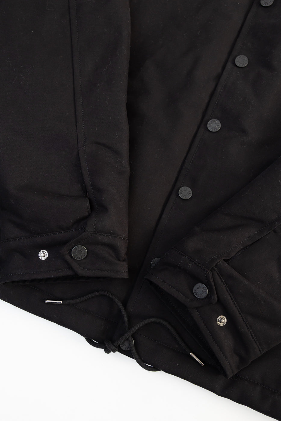 Close-up of Eat Dust Dago Jacket black cotton front hem, snap buttons, drawstring detail