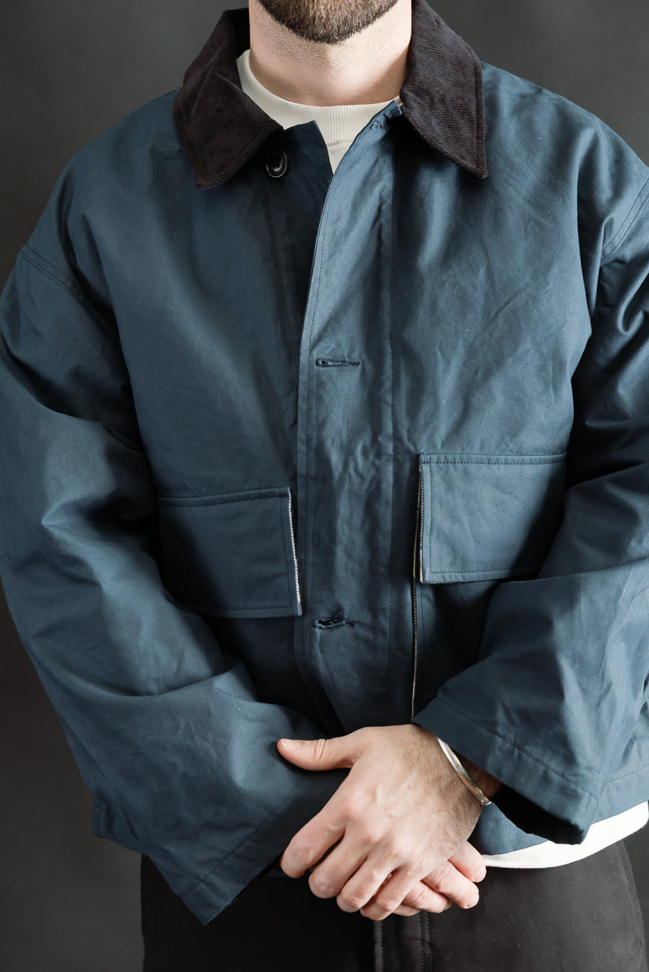Male model 5'9 165lbs wearing Eat Dust Creek Jacket, front close-up showing waxed cotton, large pockets, and corduroy collar