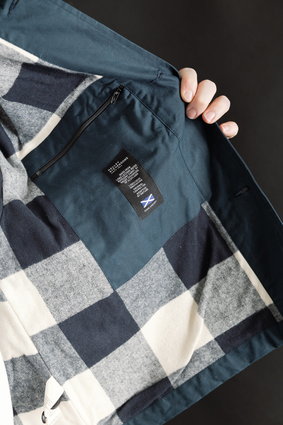 Close-up of Eat Dust Creek jacket interior left side, showing zip pocket, fabric tag, and plaid lining