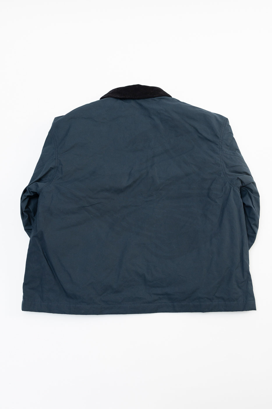Flat lay of Eat Dust dry wax cotton Creek Jacket in eclipse blue, back view, showing collar and straight hem.