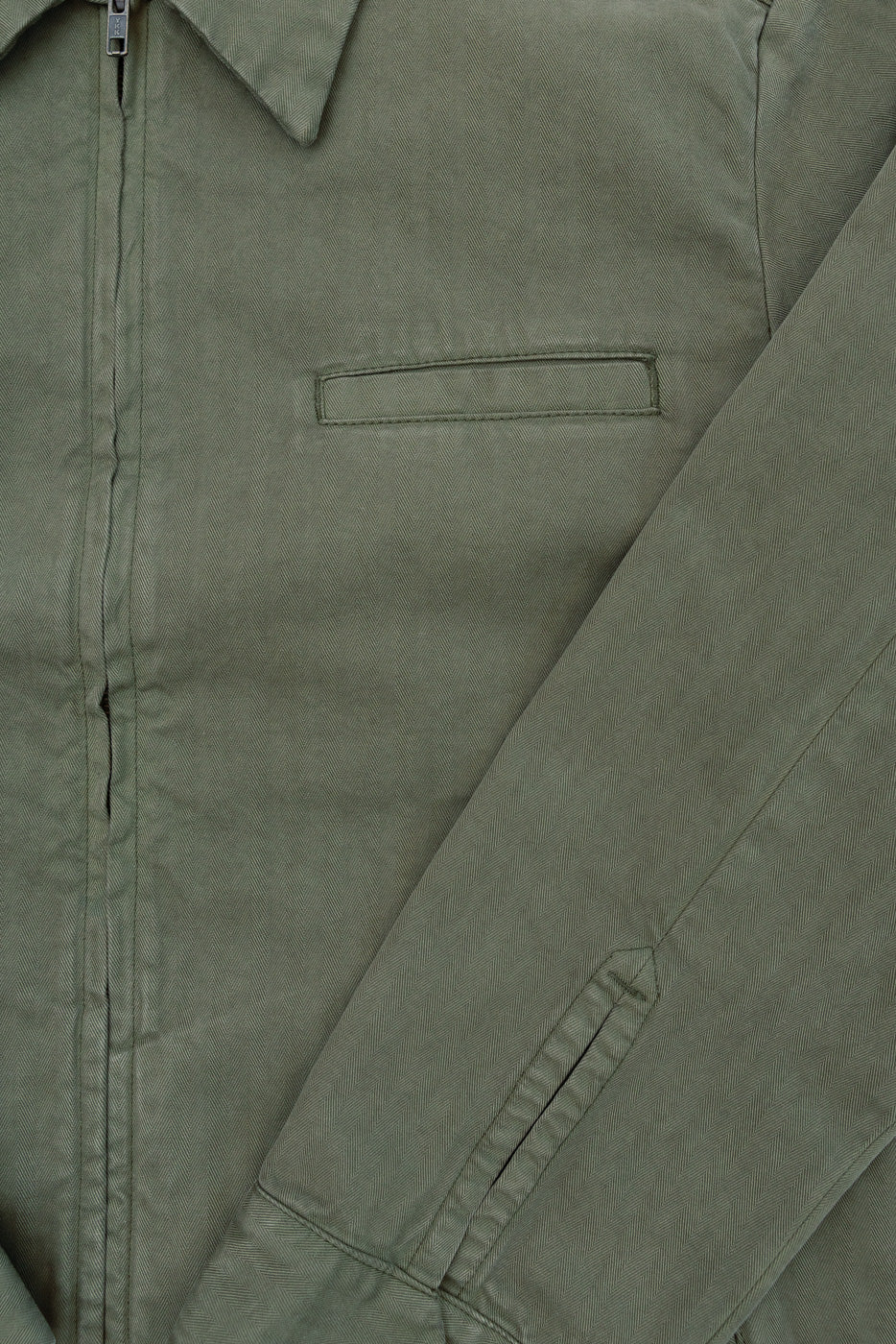 Close-up front view of olive green cotton jacket showing chest pocket and sleeve detail.