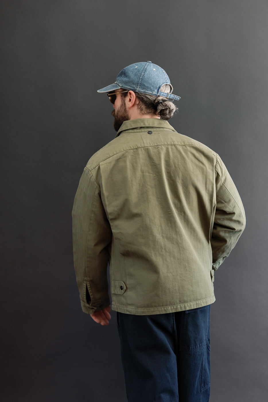 Back view of olive green jacket on male model, 5'9
