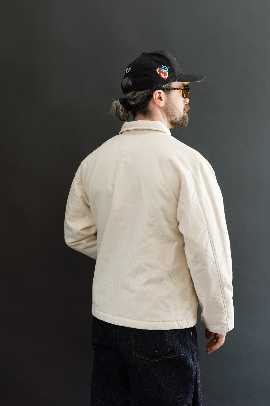 Male model 5'9, 165lbs, athletic build wearing ecru jacket, back view, full body