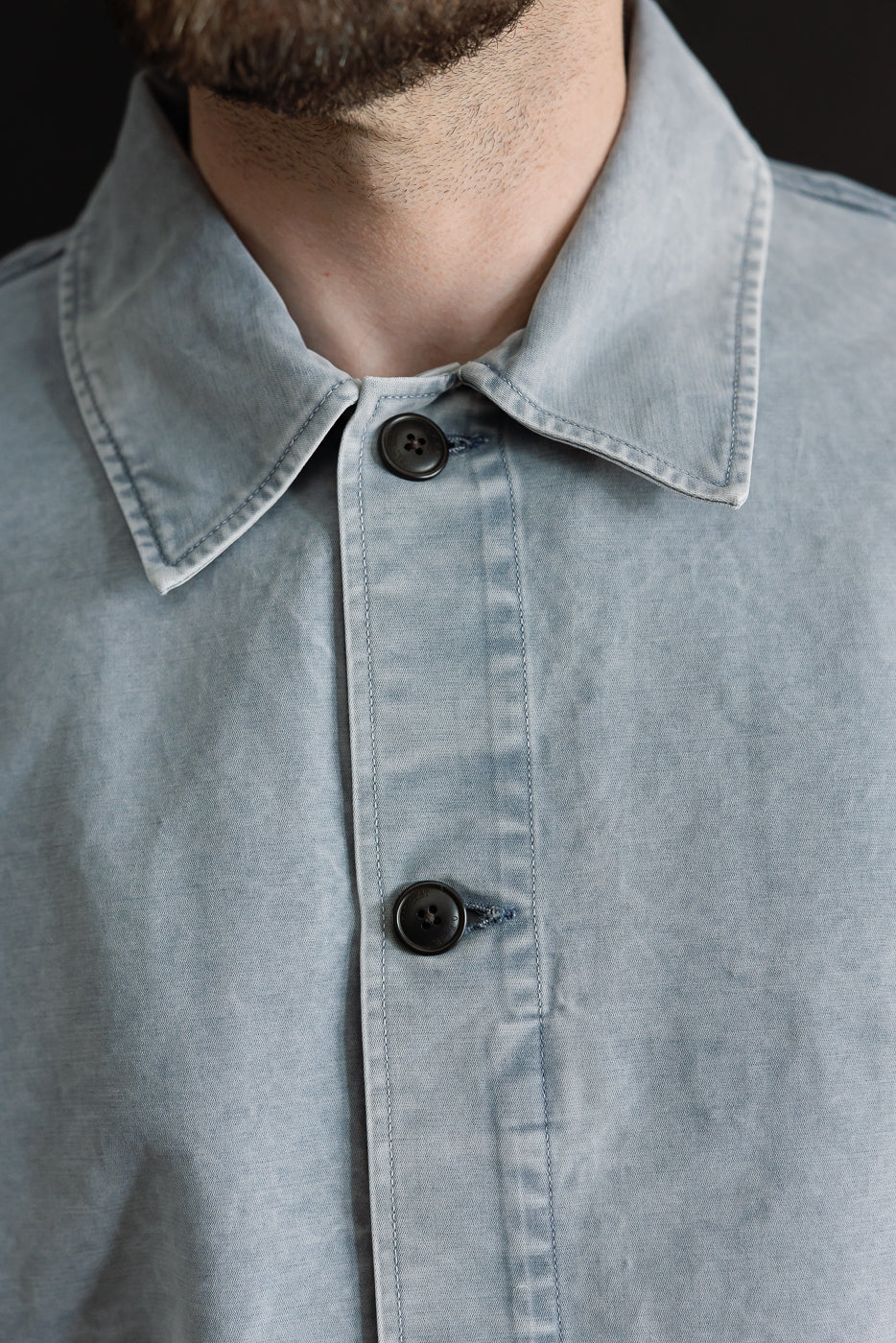 Close-up of a person wearing the M-B-006 Coach Jacket Nebraska Cotton - Coastal Blue, showcasing the soft-cotton texture, dark buttons, and relaxed fit of this premium menswear piece.