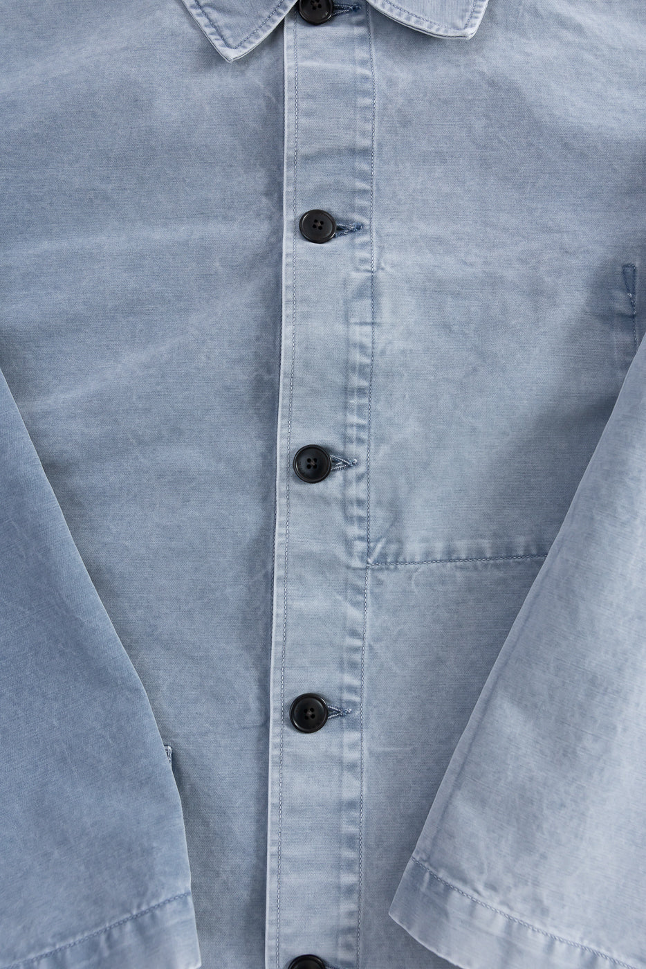 Close-up of the M-B-006 - Coach Jacket Nebraska Cotton - Coastal Blue, highlighting the light blue fabric, four dark buttons, collar, and partial sleeves, showcasing its relaxed fit and premium cotton texture.