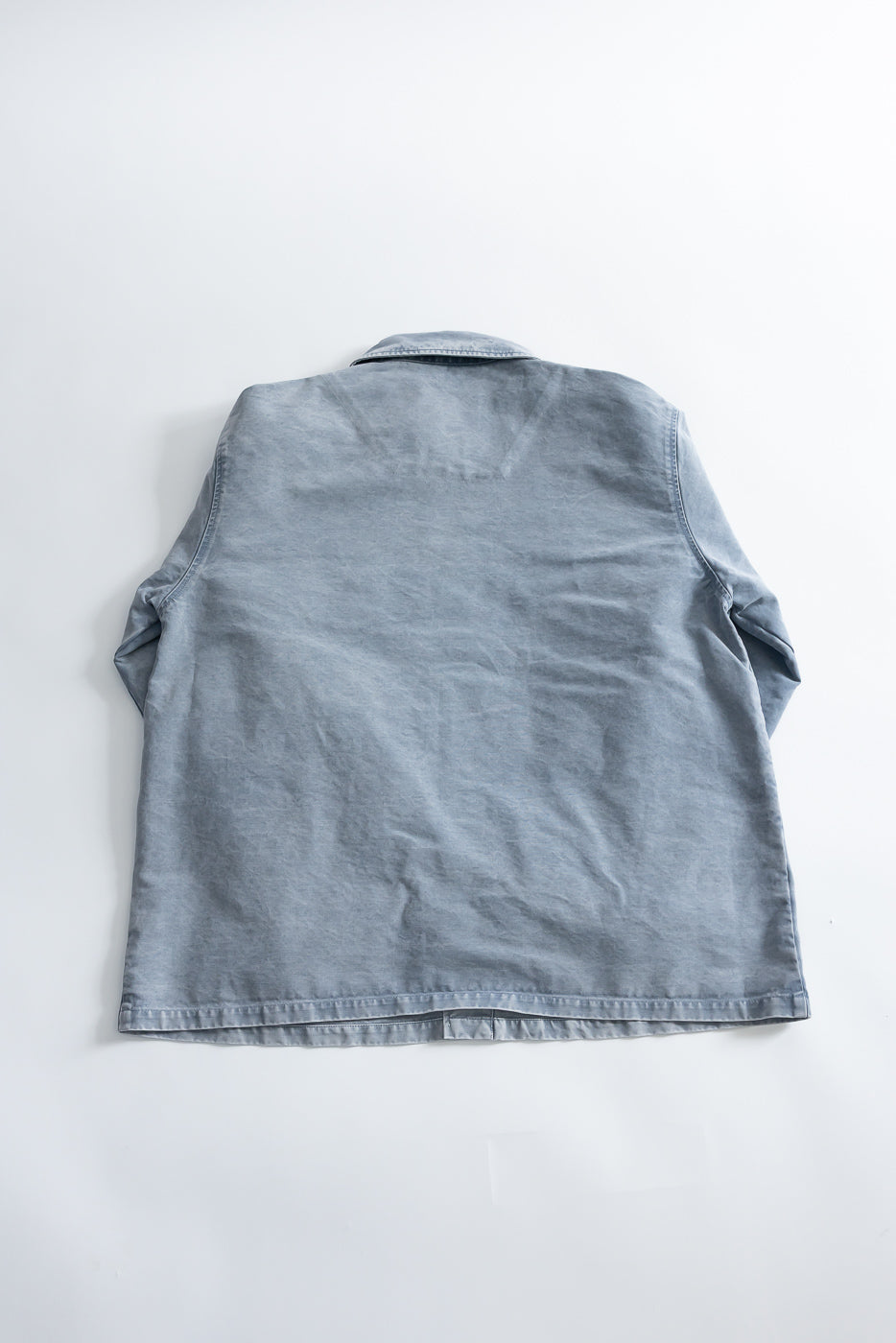 M-B-006 - Coach Jacket Nebraska Cotton - Coastal Blue laid flat, showcasing the back with a collar, slightly folded sleeves, and a straight hem. Designed with a relaxed fit and clean lines.