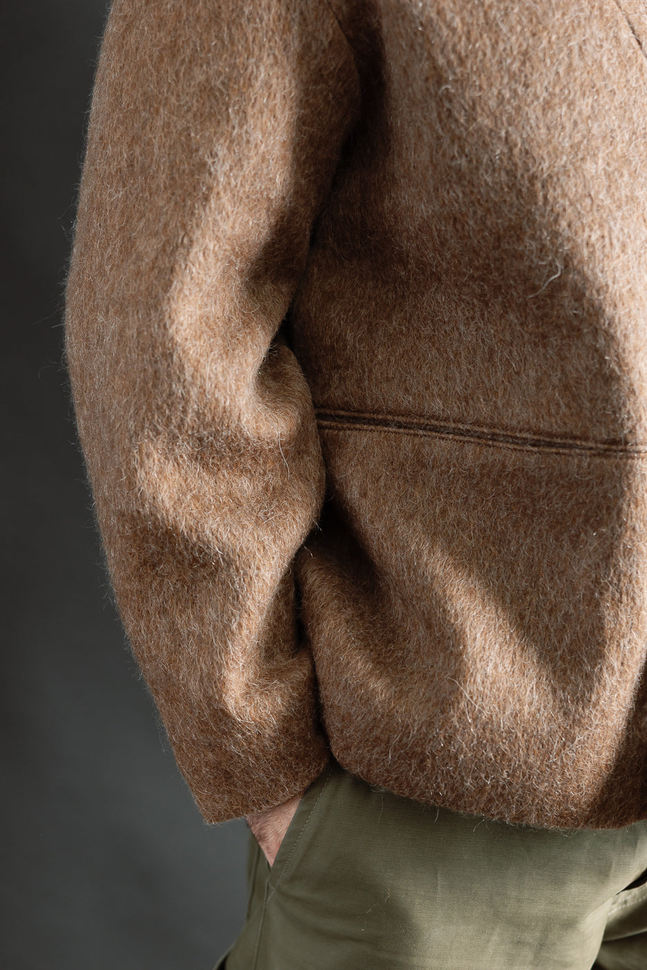 Close-up side view of men's brown mohair fleece cardigan sleeve and torso, model 5'9