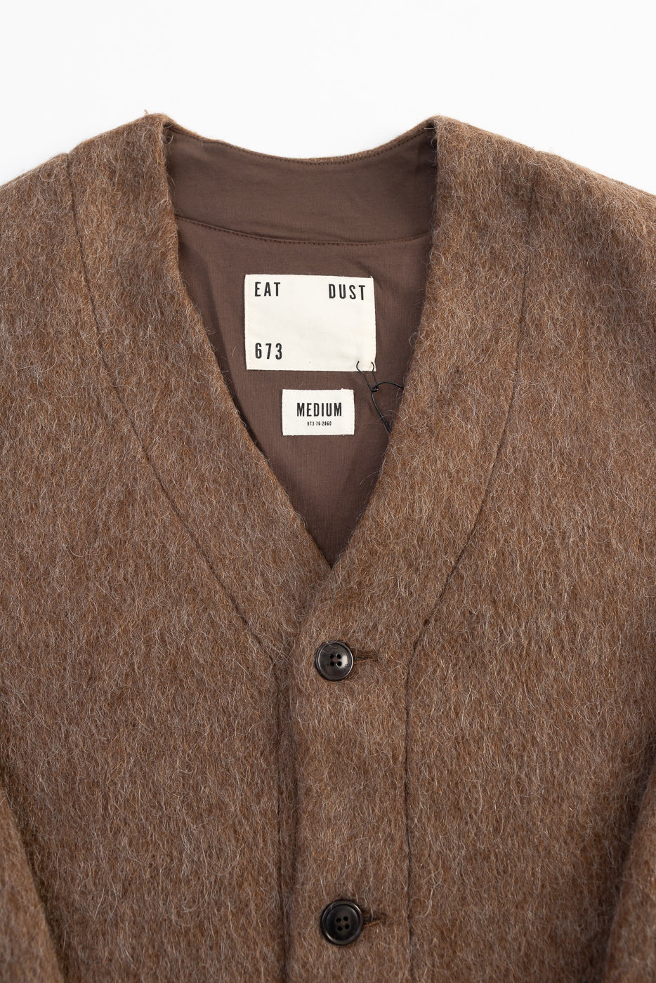 Close-up front of Eat Dust mohair fleece cardigan in java brown, showing button and inner tags